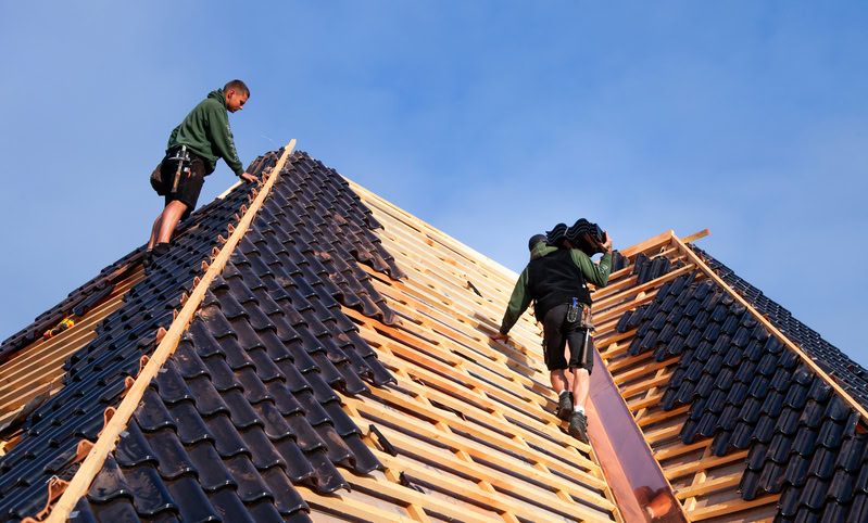 Zwei Dachdecker stehen auf einem Dach